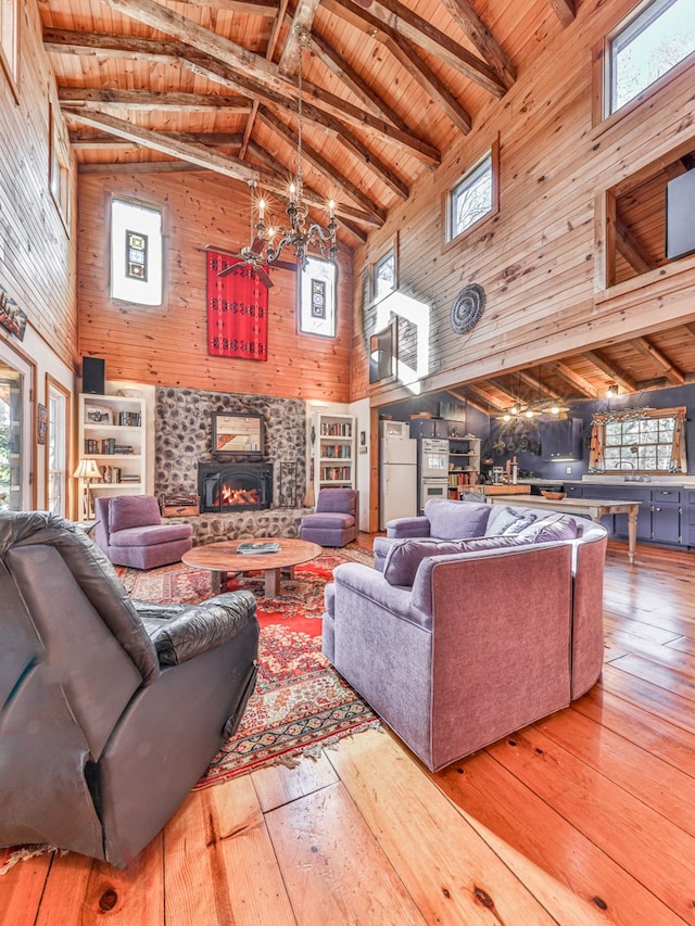 living room featuring a wood stove, high vaulted ceiling, and a healthy amount of sunlight