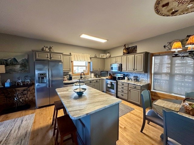 kitchen featuring stainless steel appliances, light hardwood / wood-style flooring, a kitchen island, and gray cabinetry