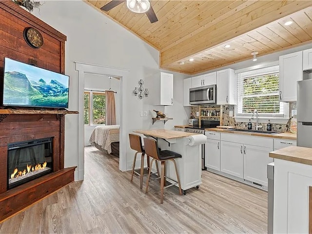 kitchen featuring stainless steel appliances, white cabinetry, sink, and wood ceiling