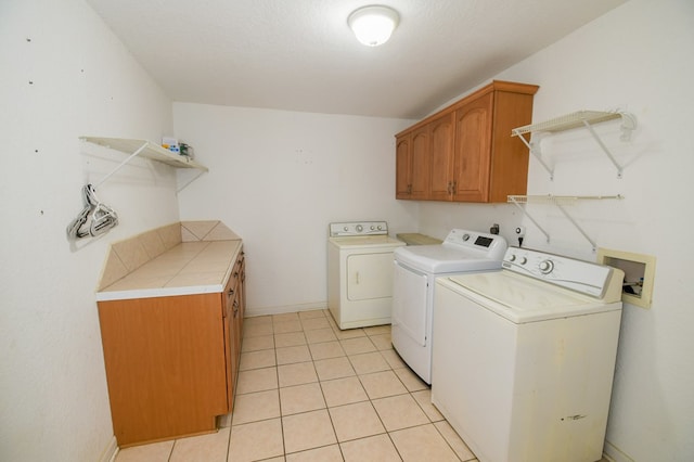 laundry area featuring cabinet space, baseboards, washer and clothes dryer, and light tile patterned flooring