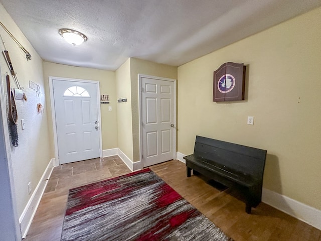 entryway with baseboards, a textured ceiling, and wood finished floors