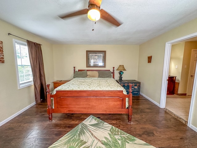 bedroom with a textured ceiling, ceiling fan, dark wood finished floors, and baseboards