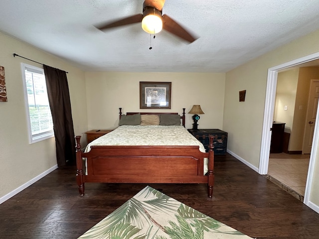 bedroom with dark wood-style floors, a ceiling fan, baseboards, and a textured ceiling