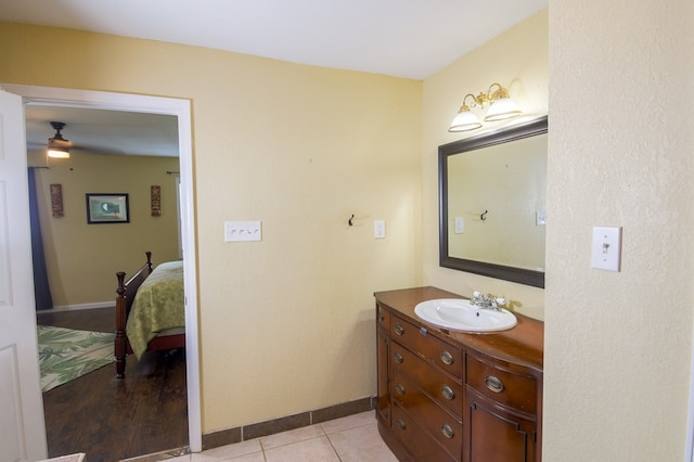 ensuite bathroom with baseboards, connected bathroom, ceiling fan, tile patterned flooring, and vanity