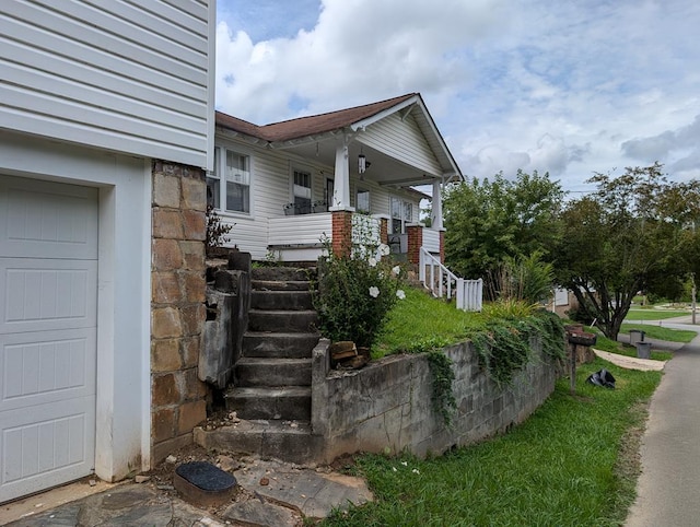 property entrance with a garage, stone siding, and a porch