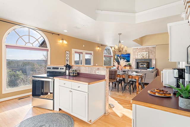 kitchen with white cabinetry, crown molding, stainless steel electric range oven, a tray ceiling, and a notable chandelier