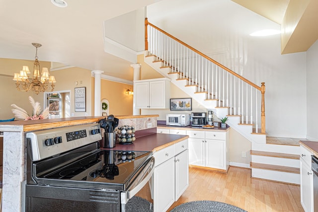 kitchen featuring ornate columns, white cabinets, stainless steel range with electric stovetop, hanging light fixtures, and light wood-type flooring