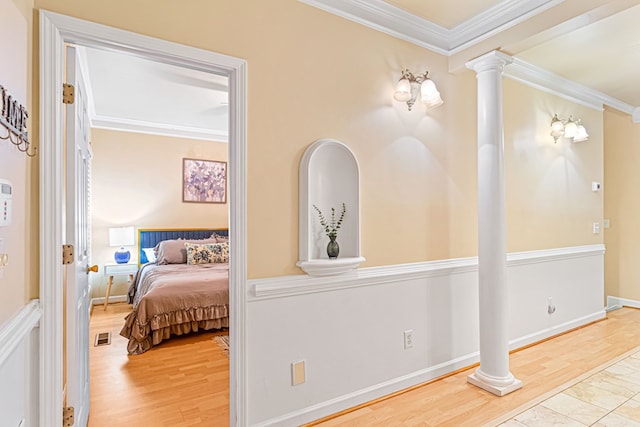 hallway featuring hardwood / wood-style flooring, ornamental molding, and decorative columns