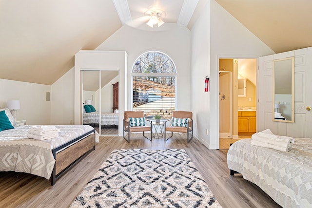 bedroom featuring high vaulted ceiling, light wood-type flooring, connected bathroom, and ceiling fan