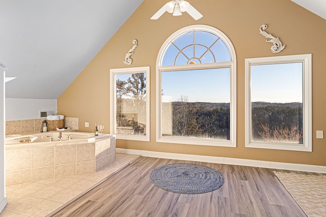 bathroom with lofted ceiling, hardwood / wood-style floors, ceiling fan, and tiled bath