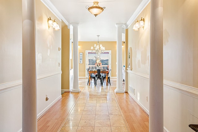 hallway with decorative columns, crown molding, and a chandelier