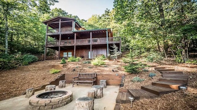 rear view of property featuring a wooden deck and an outdoor fire pit