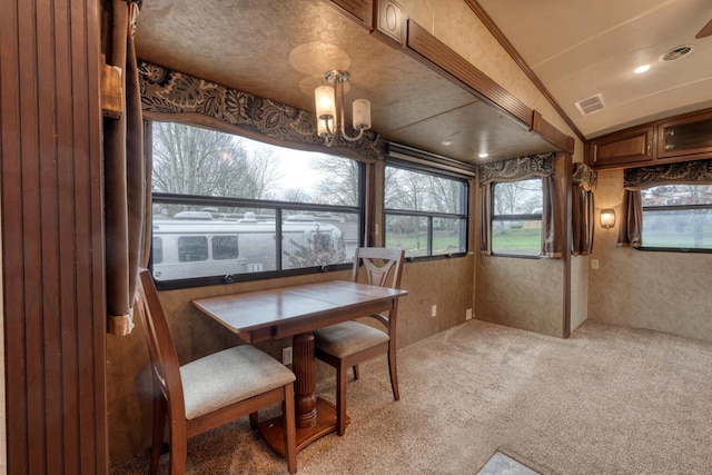 carpeted dining area with a textured ceiling, an inviting chandelier, and lofted ceiling