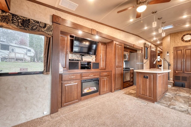 kitchen with stainless steel appliances, sink, an island with sink, and light colored carpet