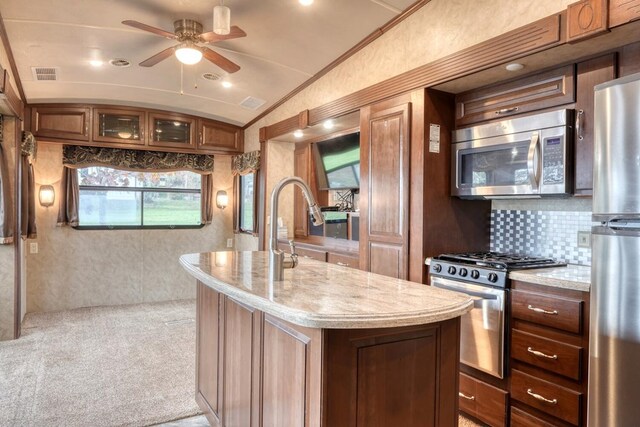 kitchen featuring ceiling fan, stainless steel appliances, light colored carpet, lofted ceiling, and a kitchen island