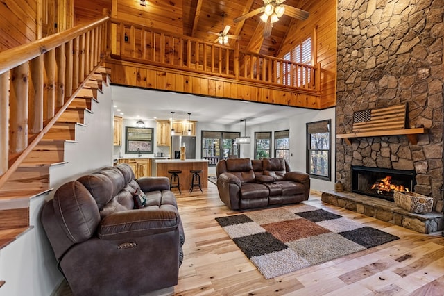 living room with beam ceiling, light hardwood / wood-style flooring, wooden ceiling, ceiling fan, and a fireplace