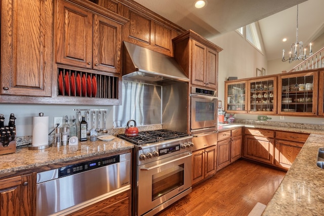 kitchen featuring appliances with stainless steel finishes, ventilation hood, vaulted ceiling, a chandelier, and light hardwood / wood-style floors