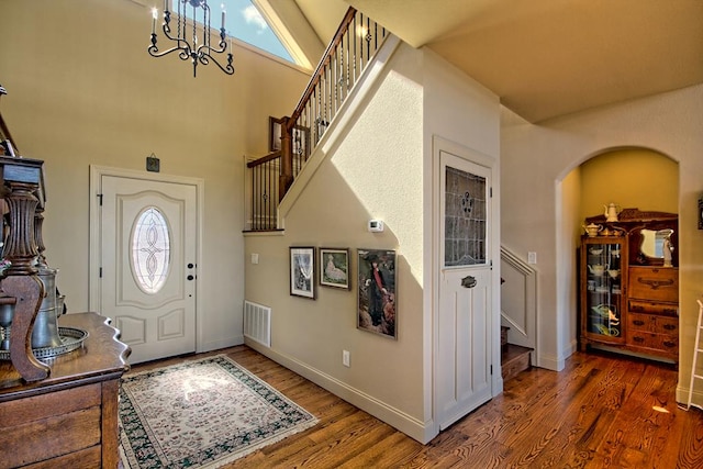 entrance foyer featuring high vaulted ceiling, a chandelier, and dark hardwood / wood-style floors