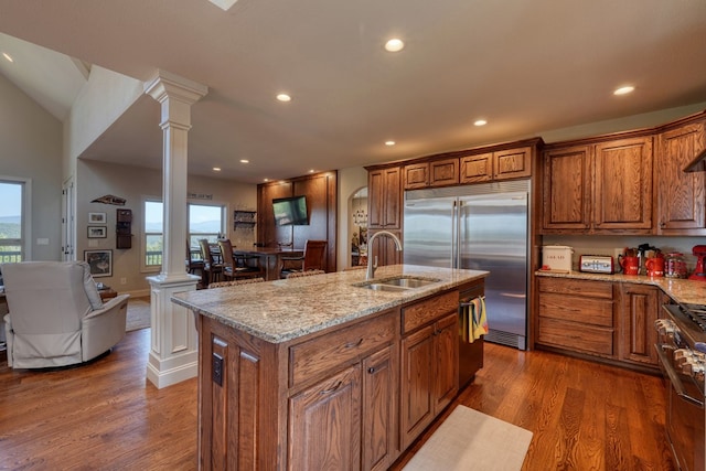 kitchen featuring decorative columns, a kitchen island with sink, sink, and dark hardwood / wood-style floors