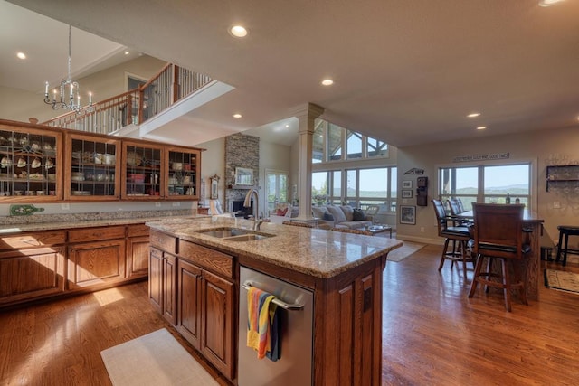 kitchen featuring hardwood / wood-style floors, decorative columns, a kitchen island with sink, and sink