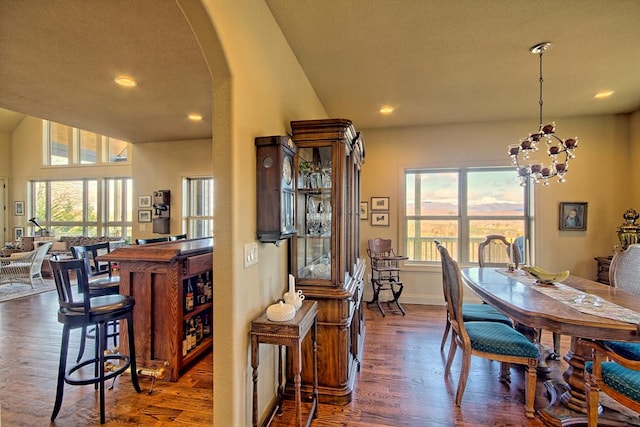 dining area featuring dark hardwood / wood-style flooring, lofted ceiling, and a chandelier