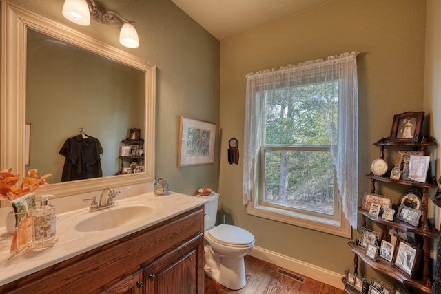 bathroom with toilet, vanity, and hardwood / wood-style flooring