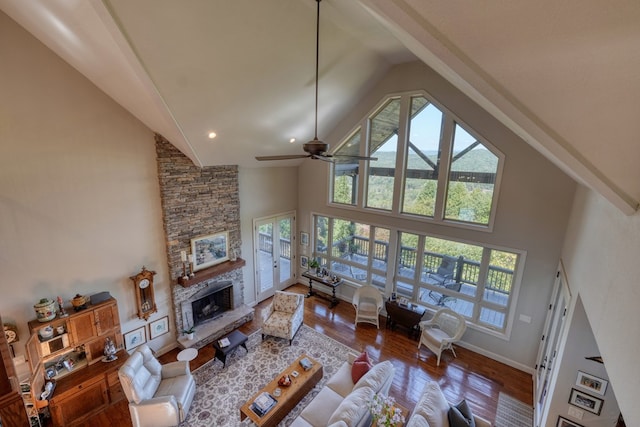 living room featuring ceiling fan, wood-type flooring, a fireplace, and high vaulted ceiling