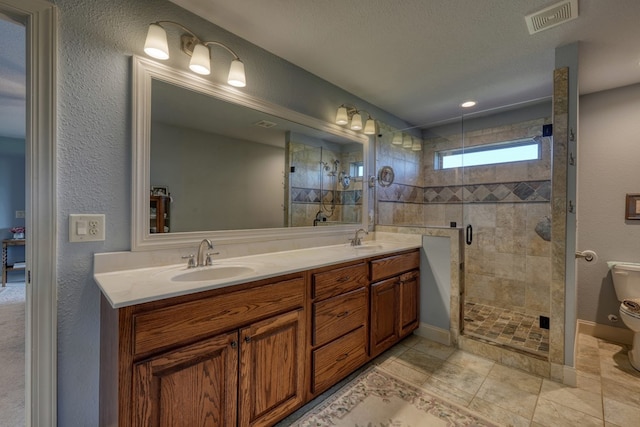 bathroom featuring vanity, a shower with door, tile patterned flooring, toilet, and a textured ceiling