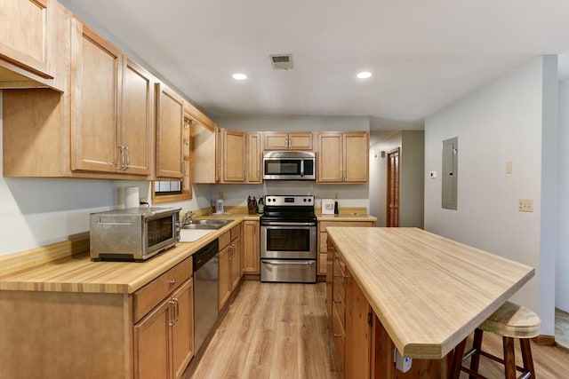 kitchen featuring appliances with stainless steel finishes, light hardwood / wood-style flooring, sink, and a breakfast bar