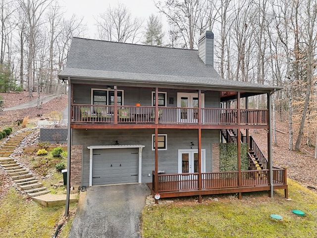 view of front of property with a garage, a chimney, aphalt driveway, stairs, and french doors