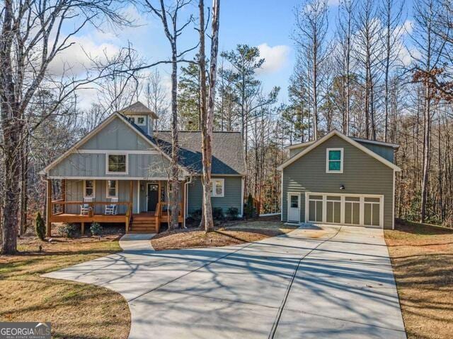 front facade with covered porch, a garage, and a front lawn