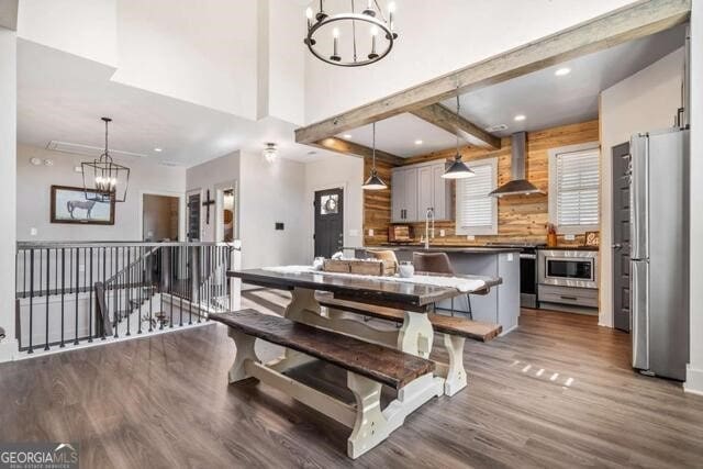 dining area with beamed ceiling, dark hardwood / wood-style flooring, wooden walls, and a notable chandelier