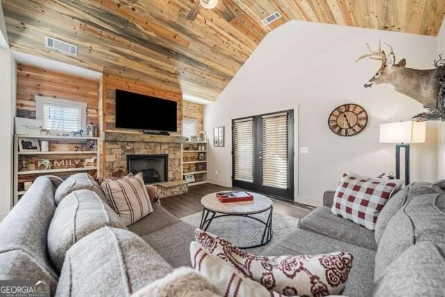 living room featuring ceiling fan, high vaulted ceiling, wooden walls, a fireplace, and wood ceiling