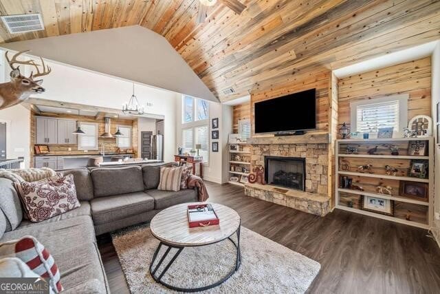 living room with wooden ceiling, high vaulted ceiling, a notable chandelier, wooden walls, and a fireplace