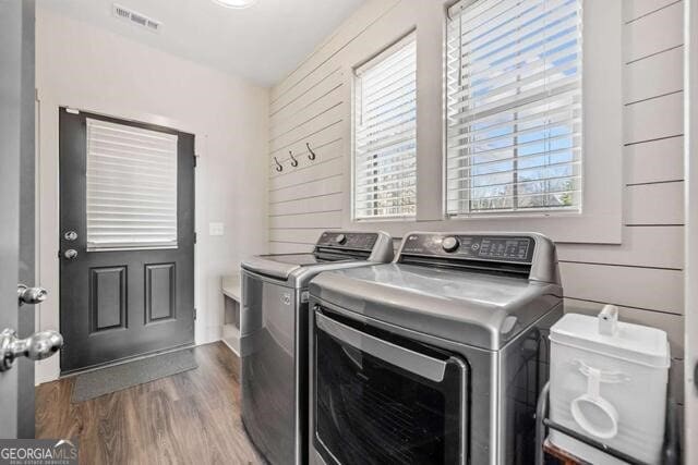 laundry area with separate washer and dryer, hardwood / wood-style flooring, and wooden walls