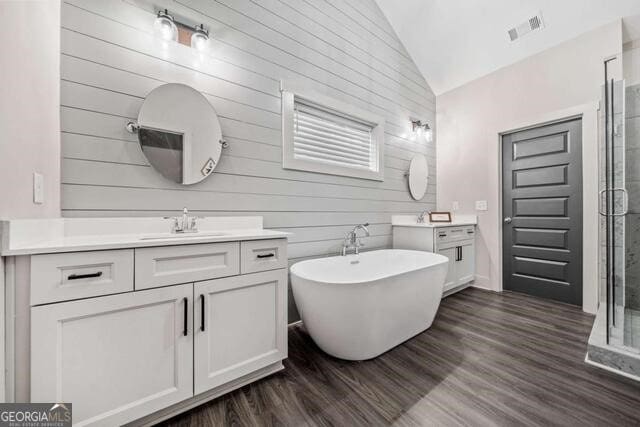 bathroom with vanity, wood walls, plus walk in shower, vaulted ceiling, and wood-type flooring