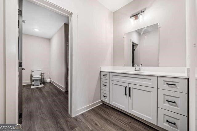 bathroom with hardwood / wood-style floors, vanity, and toilet