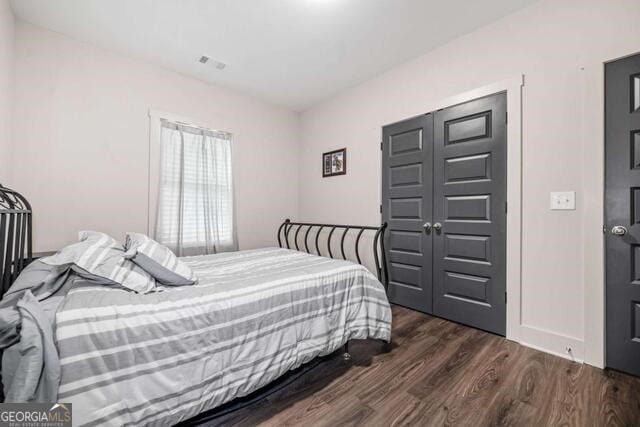 bedroom with dark wood-type flooring and a closet