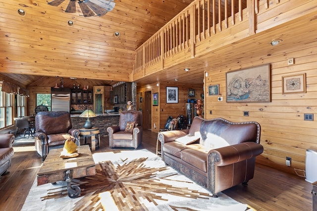 living room with hardwood / wood-style flooring, wooden walls, ceiling fan, and high vaulted ceiling