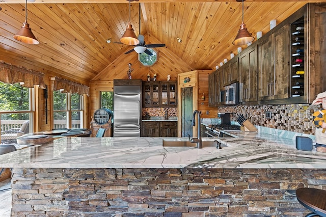 kitchen featuring pendant lighting, sink, vaulted ceiling, decorative backsplash, and appliances with stainless steel finishes