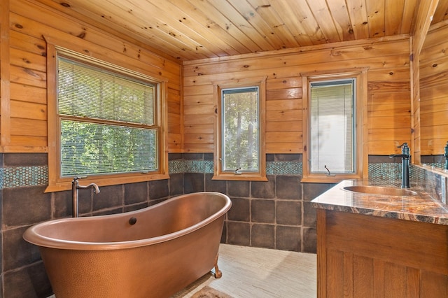 bathroom with wooden walls, a tub to relax in, wooden ceiling, and vanity