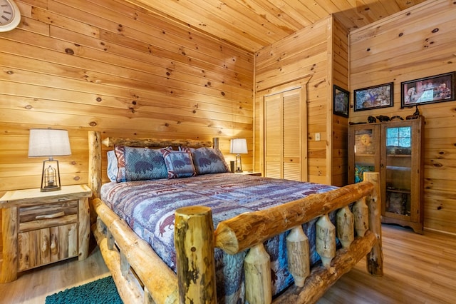 bedroom featuring wood-type flooring, wood ceiling, wooden walls, and a closet