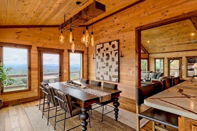 dining space with light wood-type flooring, wooden walls, high vaulted ceiling, and wood ceiling