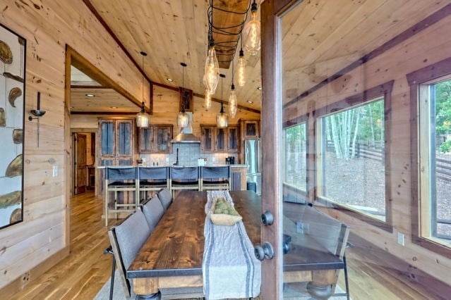 dining room with wooden walls, wood ceiling, wood finished floors, and lofted ceiling