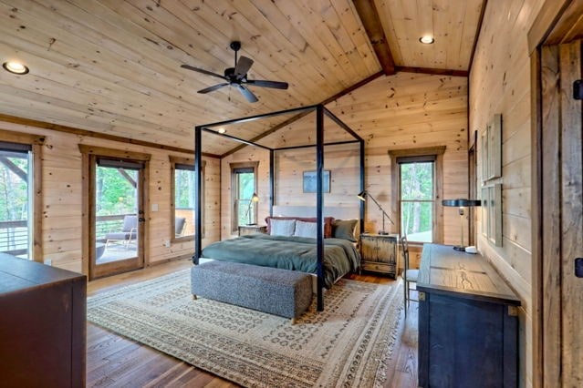 bedroom featuring lofted ceiling with beams, hardwood / wood-style flooring, wood ceiling, wooden walls, and access to outside