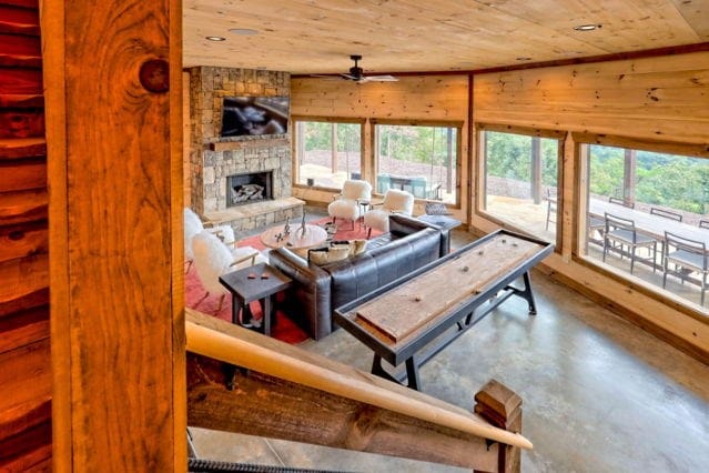 living area with wood ceiling, ceiling fan, a stone fireplace, and concrete flooring