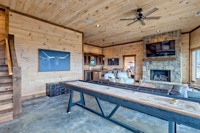 interior space featuring a fireplace, concrete floors, recessed lighting, wood ceiling, and wooden walls