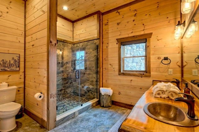 bathroom with an enclosed shower, wooden walls, vanity, and toilet