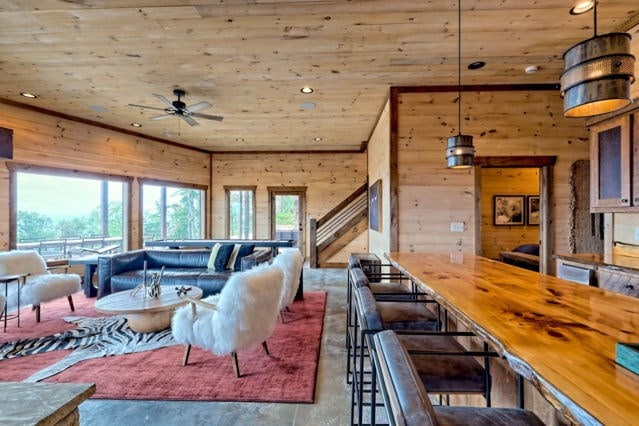 living room with wood walls, a ceiling fan, wooden ceiling, and finished concrete floors