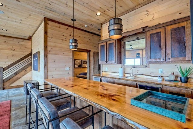 kitchen featuring decorative light fixtures, a sink, a kitchen breakfast bar, wood ceiling, and wood walls